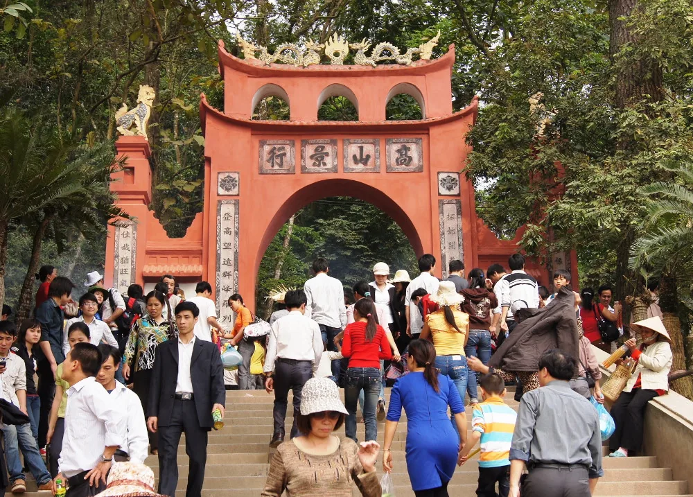 Cổng chính khu di tích Đền Hùng sơn đỏ, nhiều người đang lên các bậc thềm